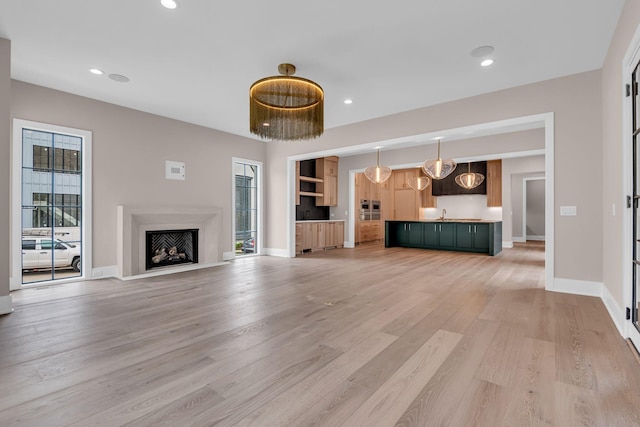 unfurnished living room featuring sink and light hardwood / wood-style flooring