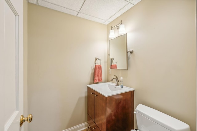 bathroom with toilet, a drop ceiling, and vanity