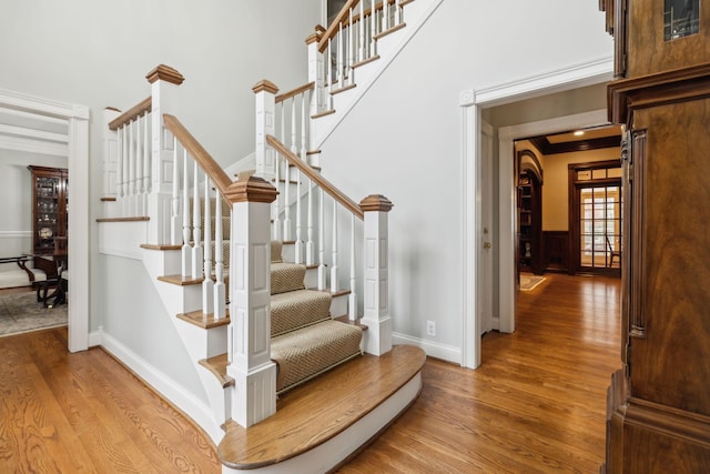 staircase with ornamental molding and hardwood / wood-style flooring