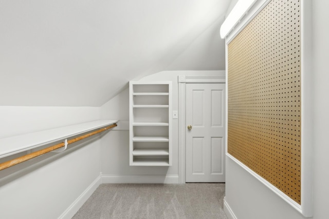 walk in closet with lofted ceiling and light carpet