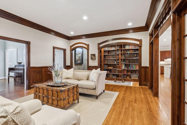 living room featuring light wood-type flooring, built in features, and ornamental molding