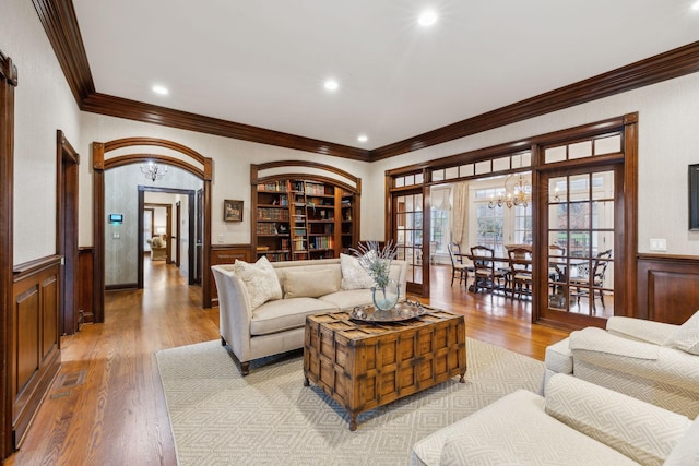 living room with ornamental molding, light wood-type flooring, and a chandelier