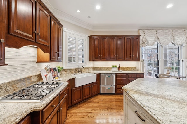 kitchen featuring sink, light stone counters, light wood-type flooring, decorative backsplash, and stainless steel gas stovetop