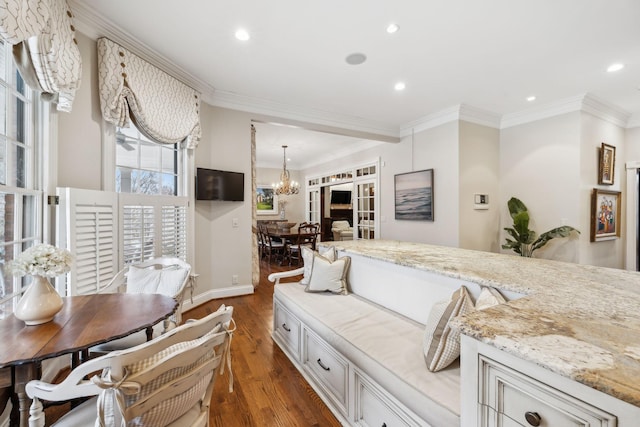 interior space with crown molding, a notable chandelier, dark hardwood / wood-style flooring, light stone counters, and white cabinets