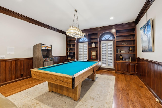 game room with wood walls, wood-type flooring, pool table, crown molding, and built in features