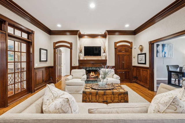 living room featuring a high end fireplace, crown molding, and light hardwood / wood-style flooring