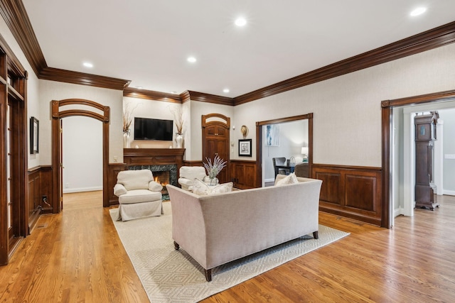 living room featuring light hardwood / wood-style floors, a premium fireplace, and ornamental molding