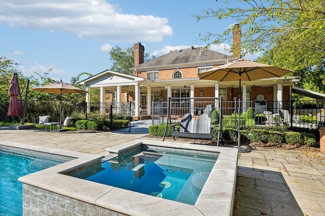 rear view of property featuring a patio and a swimming pool with hot tub