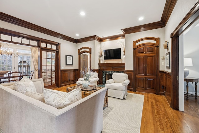 living room featuring a notable chandelier, crown molding, a fireplace, and wood-type flooring