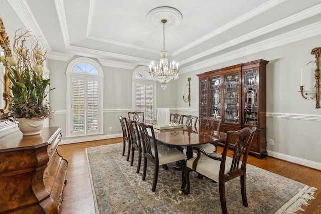 dining room with a chandelier, hardwood / wood-style floors, a tray ceiling, and crown molding