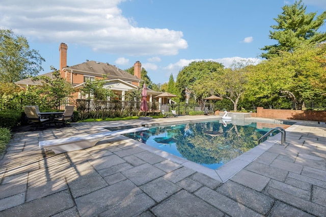 view of swimming pool with a patio area and a diving board