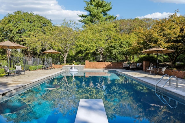 view of pool with a patio and a diving board