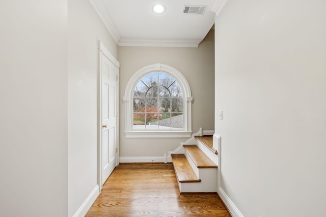 entryway with ornamental molding and light wood-type flooring