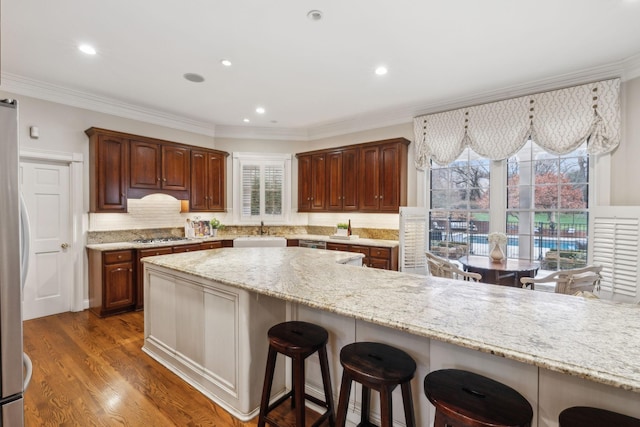 kitchen featuring sink, stainless steel appliances, a kitchen bar, tasteful backsplash, and dark hardwood / wood-style floors