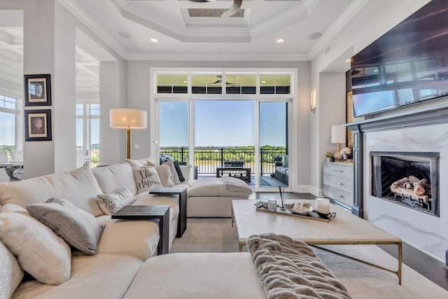 living room with a towering ceiling, a high end fireplace, and ornamental molding