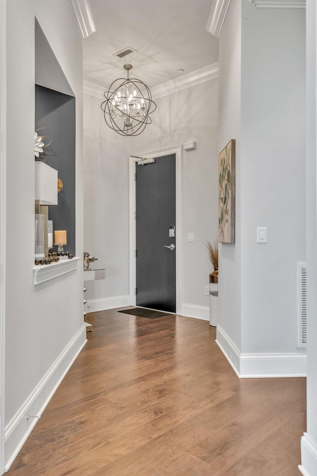 foyer with ornamental molding, a notable chandelier, and wood-type flooring