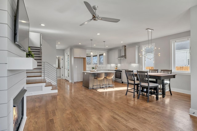 dining area featuring ceiling fan with notable chandelier, sink, and light wood-type flooring