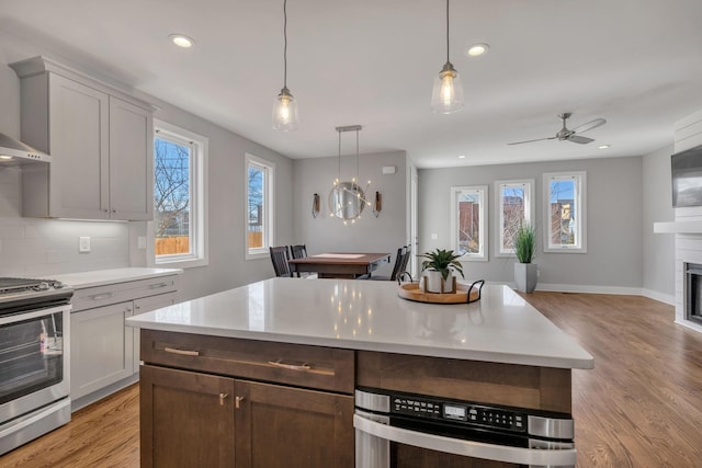 kitchen featuring pendant lighting, light hardwood / wood-style floors, backsplash, and stainless steel appliances