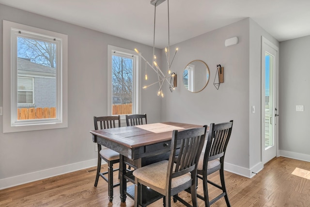 dining room with hardwood / wood-style flooring, a wealth of natural light, and a notable chandelier