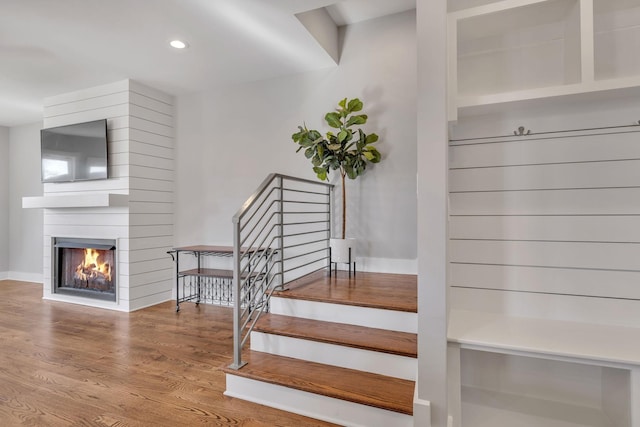 stairway with hardwood / wood-style floors and a fireplace