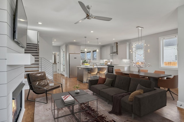 living room with ceiling fan with notable chandelier, wood-type flooring, and a healthy amount of sunlight