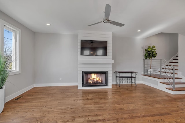 living room with hardwood / wood-style flooring, ceiling fan, and a fireplace