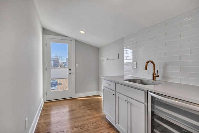 kitchen featuring tasteful backsplash, sink, white cabinets, vaulted ceiling, and beverage cooler