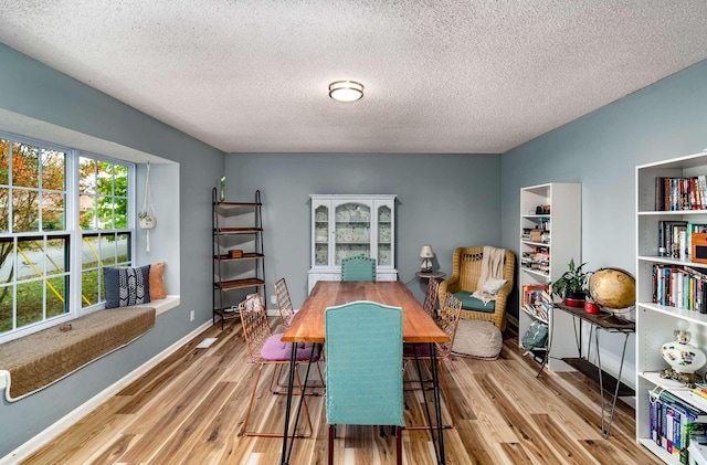 dining area with a textured ceiling and light hardwood / wood-style flooring