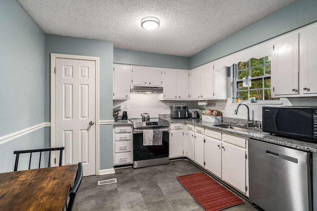 kitchen featuring stainless steel appliances, sink, white cabinetry, a textured ceiling, and dark stone countertops