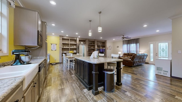 kitchen featuring a kitchen breakfast bar, stainless steel appliances, ceiling fan, pendant lighting, and dark hardwood / wood-style flooring