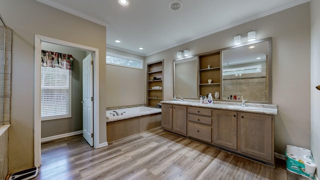 bathroom featuring a bathing tub, ornamental molding, wood-type flooring, and vanity