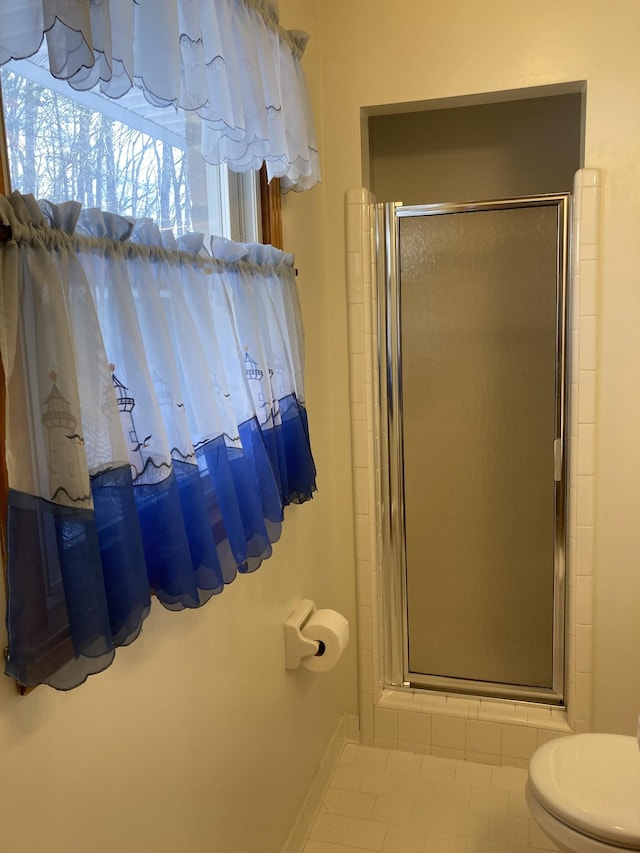 bathroom with toilet, a shower with door, and tile patterned flooring