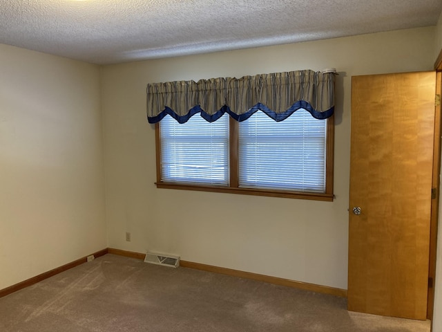 empty room with carpet floors and a textured ceiling