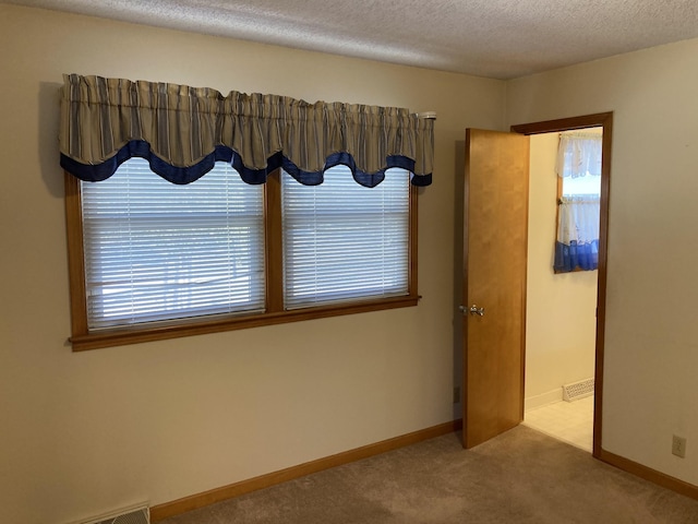 carpeted spare room featuring a textured ceiling