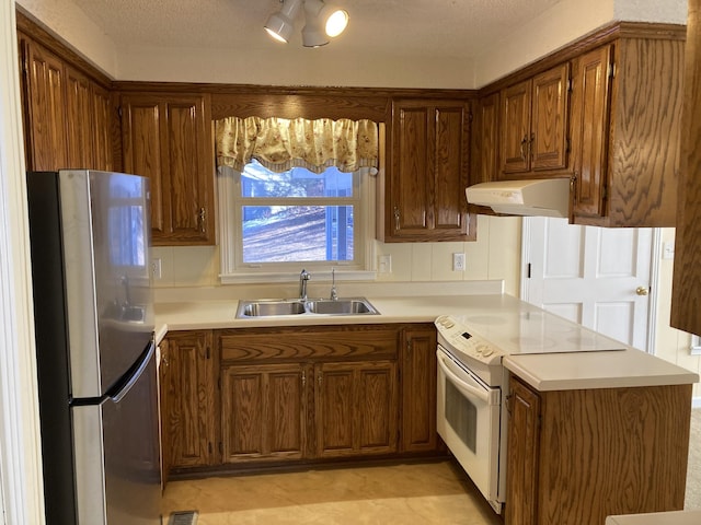 kitchen with electric range, kitchen peninsula, a textured ceiling, stainless steel fridge, and sink