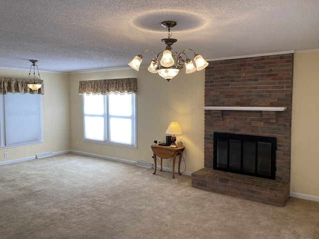 unfurnished living room with carpet flooring, an inviting chandelier, a textured ceiling, ornamental molding, and a brick fireplace