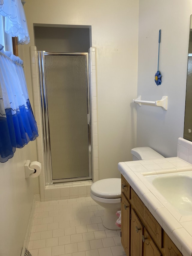 bathroom with toilet, a shower with door, vanity, and tile patterned floors