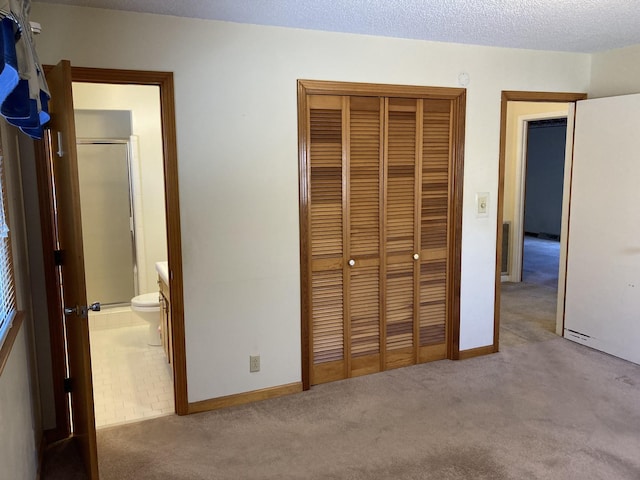 unfurnished bedroom with a textured ceiling, light colored carpet, and a closet