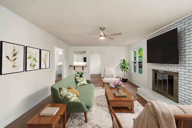 living room with wood-type flooring, a brick fireplace, and ceiling fan