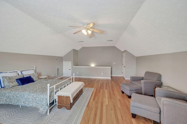 bedroom with lofted ceiling, a textured ceiling, ceiling fan, and light hardwood / wood-style floors