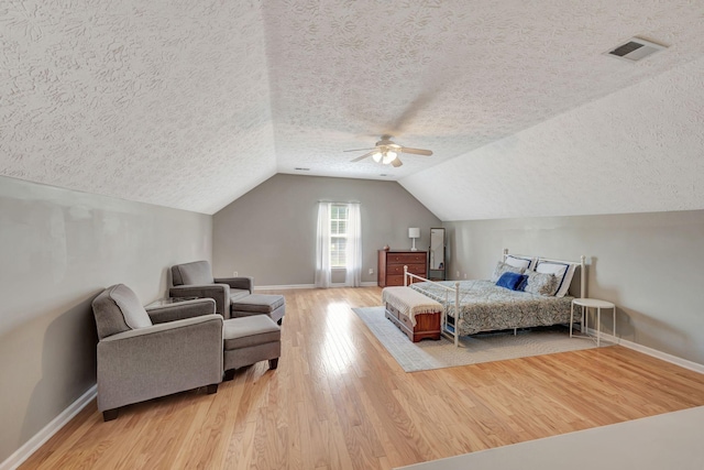 bedroom with ceiling fan, lofted ceiling, a textured ceiling, and hardwood / wood-style flooring