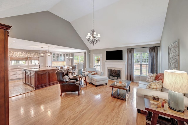 living room with sink, high vaulted ceiling, and light hardwood / wood-style floors