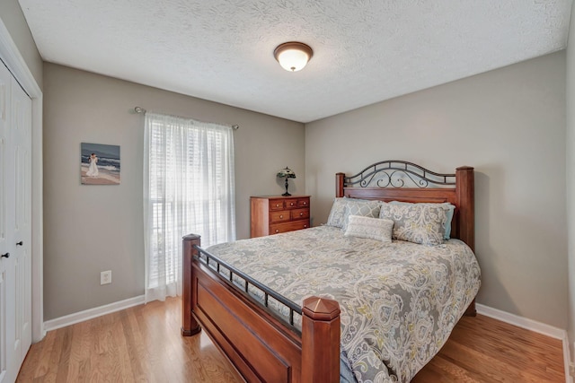 bedroom with a closet, a textured ceiling, and light hardwood / wood-style flooring