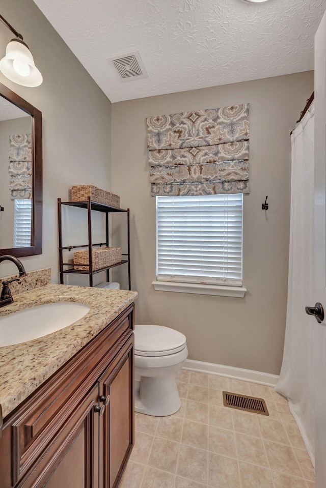 bathroom with toilet, a textured ceiling, tile patterned floors, and vanity