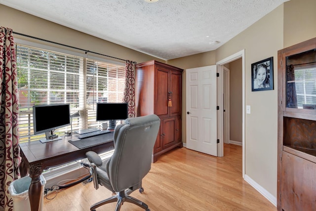 office area with a textured ceiling and light hardwood / wood-style floors