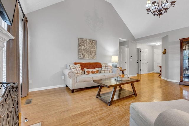 living room with high vaulted ceiling, light wood-type flooring, and a chandelier