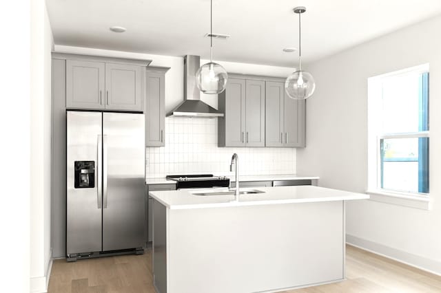 kitchen featuring stainless steel appliances, wall chimney range hood, sink, and a kitchen island with sink