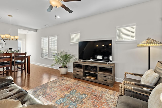 living room with ceiling fan with notable chandelier and wood-type flooring