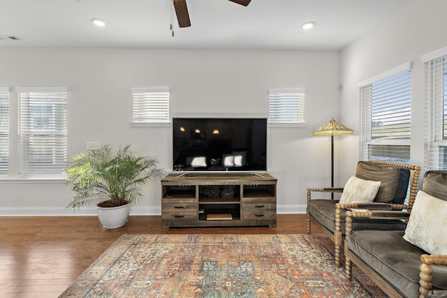 living room featuring ceiling fan, dark wood-type flooring, and a wealth of natural light