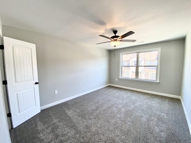 spare room with ceiling fan and dark carpet